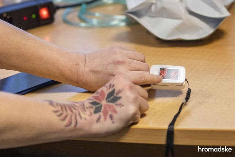 Леся Литвинова показывает родственникам человека, больного тяжелой формой COVID-19, как правильно пользоваться пульсоксиметром, 23 марта 2021 года