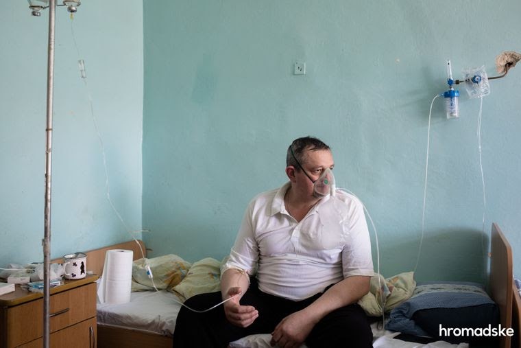 Мужчина, больной коронавирусом, сидит на кровати в инфекционном отделении больницы в городе Яремче Ивано-Франковской области