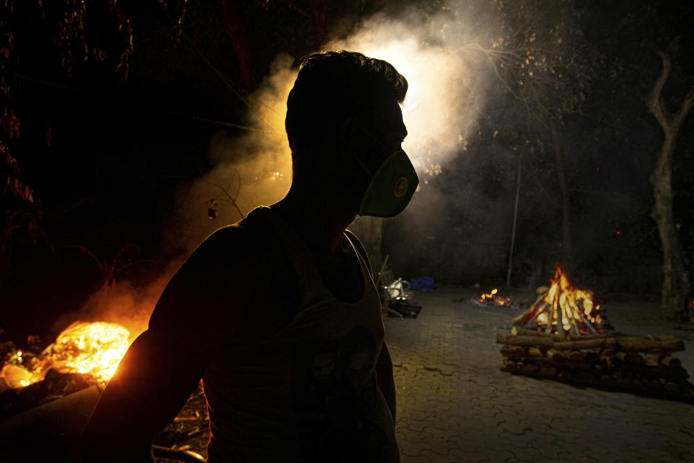 FILE - In this Sept. 14, 2020, file photo, Ramananda Sarkar, 43, who has cremated more than 450 COVID-19 victims stands by burning funeral pyres of COVID-19 victims in Gauhati, India. India’s excess deaths during the pandemic could be a staggering 10 times the official COVID-19 toll, likely making it modern India’s worst human tragedy, according to the most comprehensive research yet on the ravages of the virus in the south Asian country. (AP Photo/Anupam Nath, File)