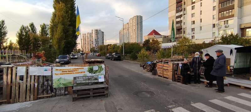 Блокпост на дорозі. З літа 2021 року місцеві мешканці сусідніх дач – Русанівських садів – виставили на міській дорозі барикаду та активізуються при спробах забудовника проїхати до своєї приватної власності. Логічно, що забудовник посилить у майбутньому навантаження на цю дорогу – нею будуть їздити сотні нових покупців квартир. Мешканцям приватних будинків це не подобається. Поки квартири не збудовані, суб’єкт, якому протидіє громада – один, забудовник. Міська влада в у цій ситуації займає позицію спостерігача