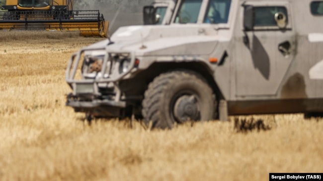 Военная машина России на украинском поле во время сбора урожая во время оккупации в Херсонской области, 21 июля 2022 года