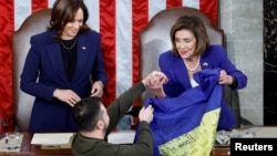 Спікерка Палати представників США Ненсі Пелосі (D-CA) отримує український прапор від Президента України Володимира Зеленського, стоячи поруч з віце-президенткою США Камаллю Гарріс, під час спільного засідання Конгресу США в залі палати Капітолію США у Вашингтоні, США, 21 грудня 2022. REUTERS/Evelyn Hockstein
