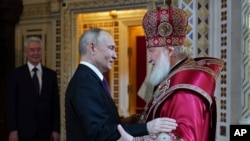 Патриарх Русской православной церкви Кирилл (справа) поздравляет президента России Владимира Путина после службы православной пасхальной службы в храме Христа Спасителя в Москве, Россия, воскресенье, 16 апреля 2023 г. Слева стоит мэр Москвы Сергей Собянин. (Олег Варов, пресс-служба РПЦ через AP)