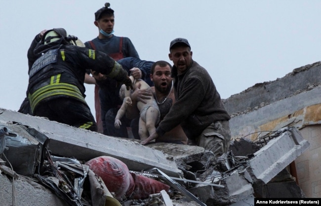 Сотрудники службы чрезвычайных ситуаций и волонтеры спасают ребенка после удара армии РФ по жилому многоэтажному дому в Славянске Донецкой области, 14 апреля 2023 года dqxikeidqxidqrant