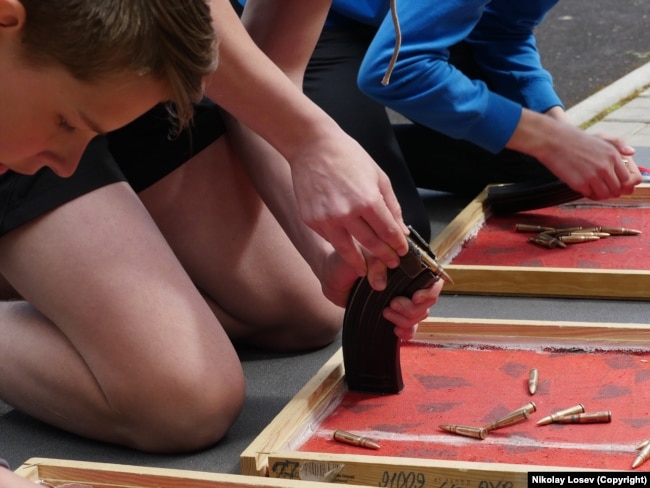 Участники российской военной игры «Зарница» разбирают и собирают автомат Калашников.