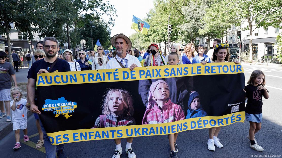 Учасники демонстрації на підтримку України в Парижі несуть плакат із закликом повернути депортованих дітей з РФ, 24 серпня 2025 року dqxikeidqxiqqdant